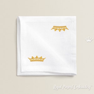 May include: White linen napkin with two gold embroidered crowns. The napkin is folded in half and the embroidery is visible on both sides.