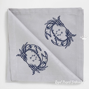 May include: Two blue embroidered crabs on a gray linen napkin. The napkin is folded in half and the text "Royal Present Embroidery" is visible in the bottom right corner.