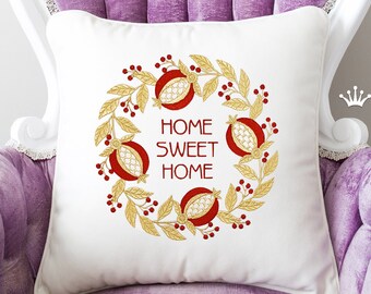 May include: White throw pillow with embroidered gold pomegranate wreath and the text "Home Sweet Home" in red.