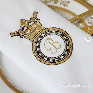 Peut inclure: Couronne brodée en or avec un cercle à carreaux noirs et blancs avec la lettre B au centre. La broderie est sur un fond de tissu blanc. Le texte "Royal Present Embroidery™" est en bas de l'image.