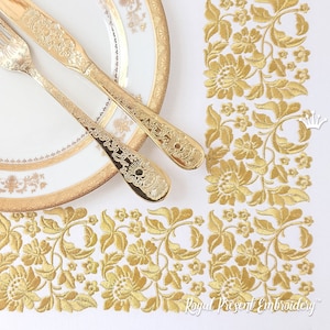 May include: Gold embroidered floral design on a white tablecloth with a gold-rimmed plate and gold silverware.