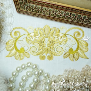Puede incluir: Diseño de bordado dorado con intrincados patrones florales. El diseño presenta un motivo central con dos piezas laterales simétricas. El bordado está sobre un fondo de tela blanca.