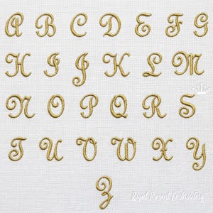 May include: Gold embroidered uppercase alphabet letters A through Z, in a cursive script, displayed on a white fabric background. The letters are in a classic, elegant font style. The image includes the text "Royal Present Embroidery".