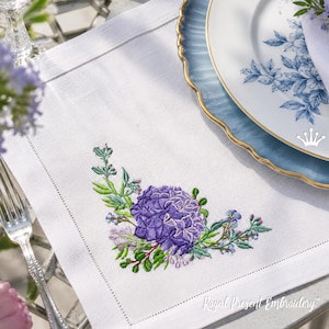 Peut inclure: Une serviette en tissu blanc de forme carrée ornée d'une broderie machine détaillée représentant un bouquet d'hortensias violets avec des feuilles et des tiges vertes, située dans le coin inférieur, avec un ourlet ajouré sur les bords.