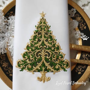 Op de afbeelding: Witte stoffen servet met een geborduurd kerstboomontwerp. De boom heeft groene en gouden filigraan details, een gouden ster en een decoratieve gouden basis. De tekst "Royal Present Embroidery" staat in de rechter benedenhoek.
