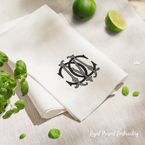 Może przedstawiać: Biały lniany ręcznik kuchenny z haftowanym czarnym monogramem liter "MCC" w ozdobnym kroju pisma. Ręcznik jest złożony na pół, a monogram znajduje się pośrodku ręcznika.