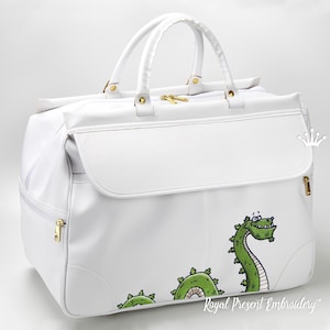 Peut inclure: Sac de voyage blanc avec fermetures éclair et poignées dorées. Un dragon de dessin animé vert est brodé sur le côté. Le sac a une poche à rabat et le texte "Royal Present Embroidery".