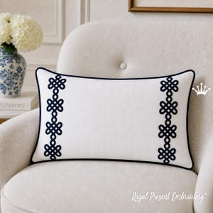 May include: White rectangular pillow with navy blue embroidered knot designs on each side. The pillow has a navy blue border and is placed on a white armchair. The text "Royal Present Embroidery" is visible.