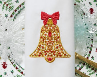 Könnte beinhalten: Goldene Weihnachtsglocke mit roter Schleife Stickerei Design. Die Glocke hat ein detailliertes Filigranmuster mit roten Juwelen. Das Design ist auf einem weißen Stoffhintergrund.