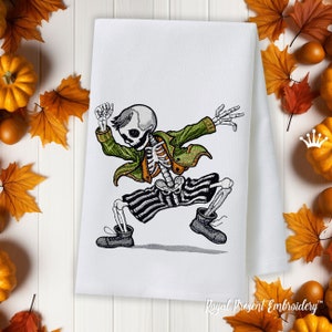 May include: Embroidered kitchen towel featuring a skeleton wearing a green jacket and striped pants, dancing with a playful expression. The towel is white with a subtle texture.