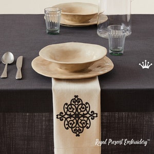 May include: A white linen napkin with a black embroidered design on a dark grey tablecloth. The design is a stylised floral pattern. The text "Royal Present Embroidery" is visible at the bottom of the image.