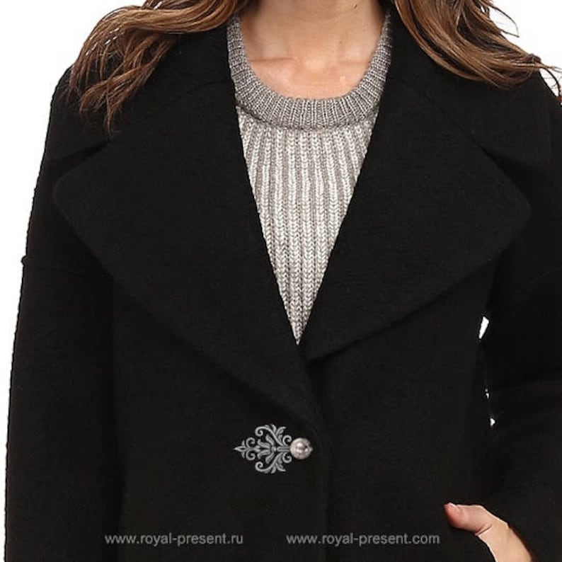 May include: A black wool coat with a large collar and a decorative silver brooch on the lapel. The coat is worn over a gray sweater.