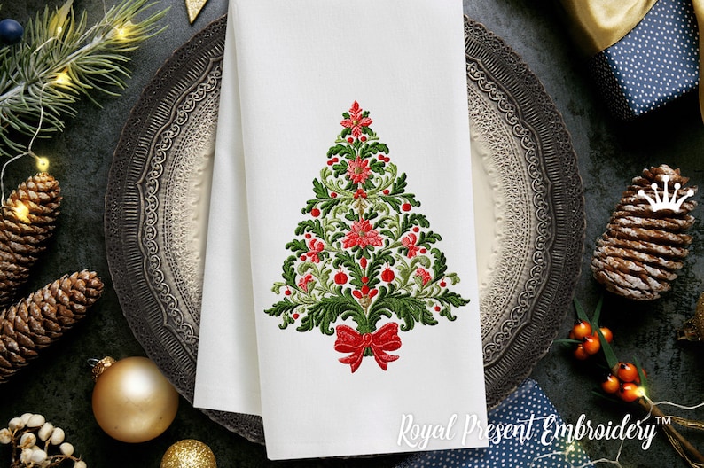 K&ouml;nnte beinhalten: Ein besticktes wei&szlig;es K&uuml;chentuch mit einem gr&uuml;nen und roten Weihnachtsbaumdesign. Der Baum ist mit roten Schleifen und roten Beeren verziert. Der Text "Royal Present Embroidery" befindet sich am unteren Rand des Tuchs.