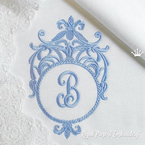 May include: A blue embroidered monogram with a decorative floral design and the letter "B" in the center. The monogram is surrounded by a rope-like border.