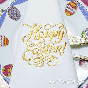 May include: A white napkin with gold embroidery that reads "Happy Easter!"  The napkin is folded and placed on a plate with a colorful Easter egg design.