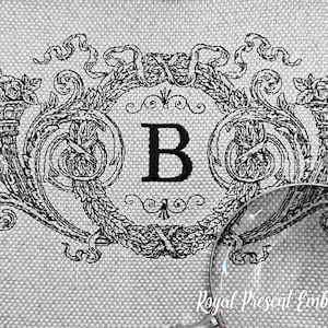 Pode incluir: Desenho de bordado em preto e branco com uma letra estilizada "B" cercada por uma coroa de folhas e flores. O desenho está sobre um fundo de tecido de linho branco. O texto "Royal Present Embroidery" é visível na parte inferior da imagem.