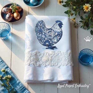 May include: White kitchen towel with a blue and white floral design of a chicken embroidered on it. The towel has a white lace trim and the words "Royal Present Embroidery" are printed at the bottom.