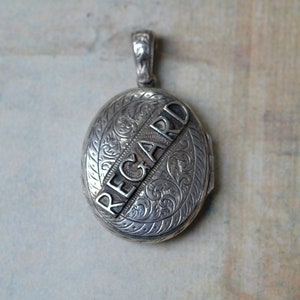 May include: Silver locket with an engraved floral design and the word "REGARD" on the front.