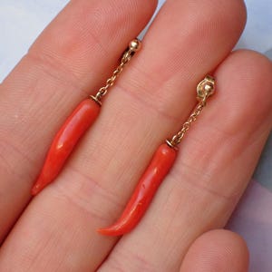 May include: A pair of dangle earrings with red coral chili pepper charms and gold chains.