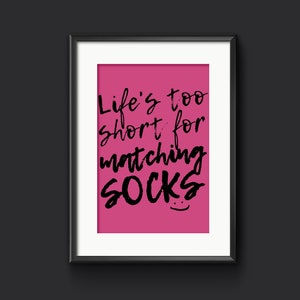 May include: A framed print with a pink background and black text that reads "Life's too short for matching socks".