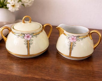 Juego de lechera y azucarero de porcelana antigua con asas doradas, pintado a mano con motivos florales Art Déco, estilo francés.