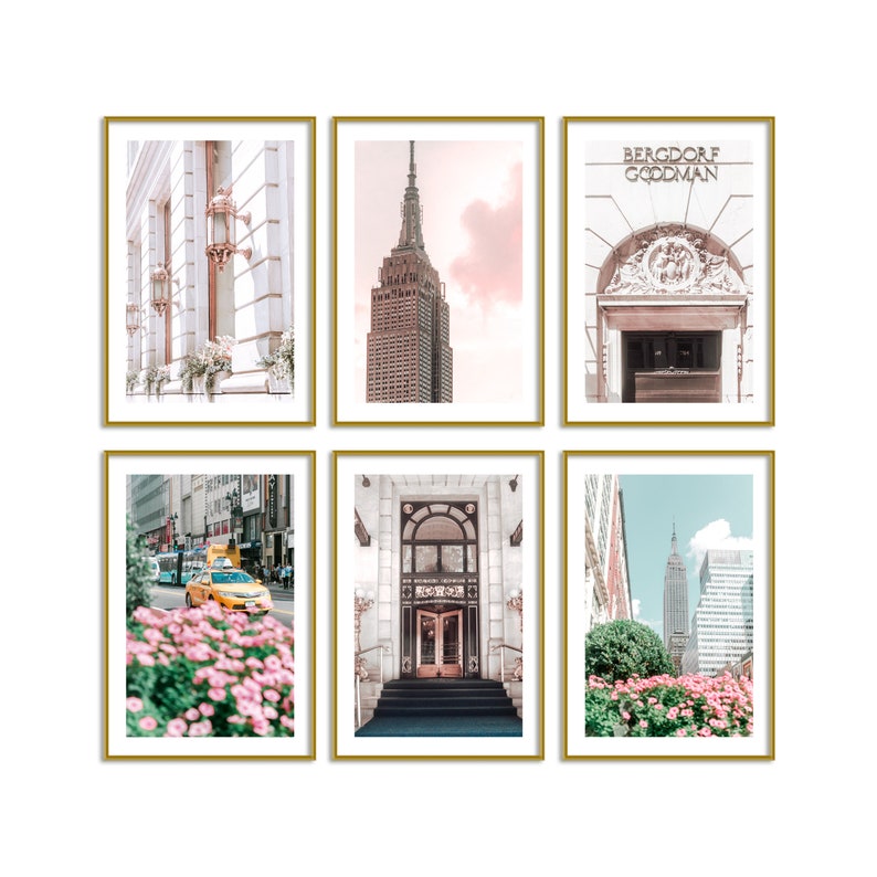 May include: Six framed prints with gold borders. The prints feature architectural images of New York City, including the Empire State Building, Bergdorf Goodman, and a yellow taxi cab. The color palette includes pink, white, and gold.