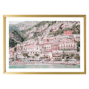 May include: A framed print of a coastal Italian town. The image features colorful buildings cascading down a hillside to a beach. The print is set in a gold-colored frame, adding a touch of elegance to the scenic view.