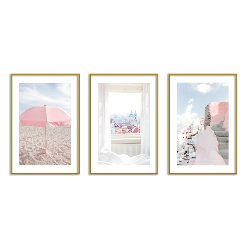 May include: Three framed prints with a pink beach umbrella, a window view of a city skyline, and a pink building with steps leading up to it.
