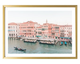 May include: A view of a canal in Venice, Italy, with colorful buildings lining the water. A gondola is in the foreground, and there are several boats docked along the canal.