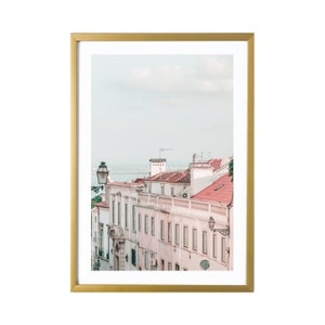 May include: A framed photograph of a street scene in a European city. The buildings are painted in soft pink and white with red tile roofs. A street lamp is visible in the foreground.