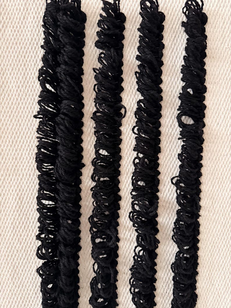 Peut inclure: Quatre bandes de tissu noir avec une texture pliss&eacute;e, dispos&eacute;es verticalement sur un fond blanc.