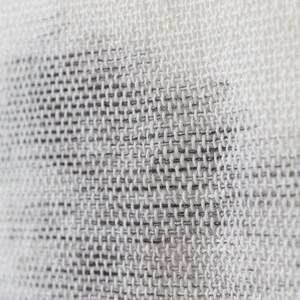 May include: Close-up of a white woven fabric with a subtle pattern. The fabric has a fine, even weave and a slightly textured surface.