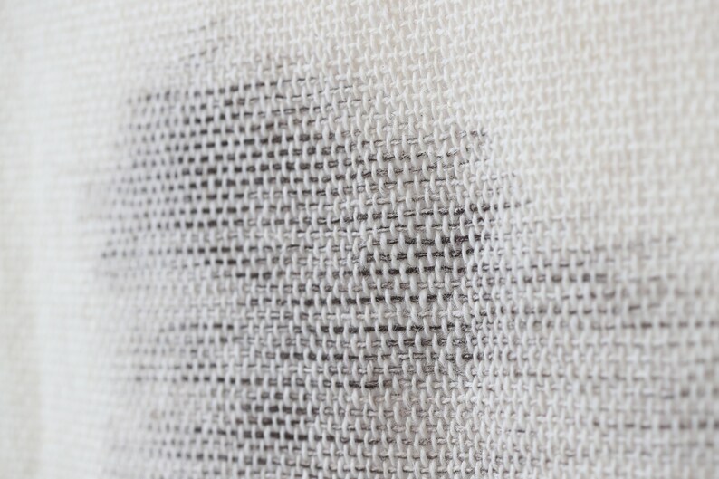 May include: Close-up of a white woven fabric with a subtle pattern. The fabric has a fine, even weave and a slightly textured surface.