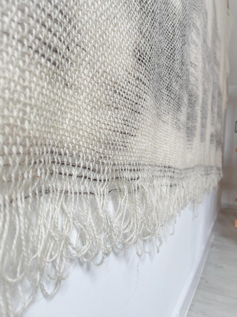 May include: A white woven wall hanging with a fringe border. The hanging has a textured, woven pattern.