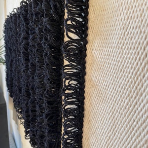 Peut inclure: Bordure de franges noires sur un fond de tissu tiss&eacute; textur&eacute;.