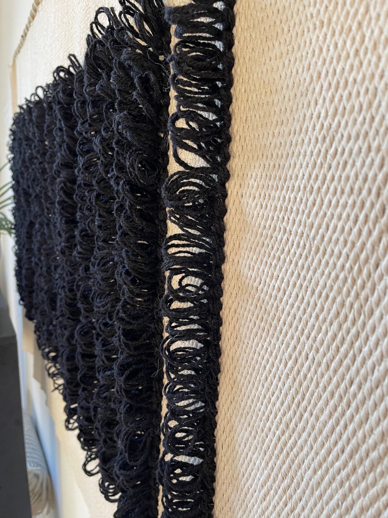 Peut inclure: Bordure de franges noires sur un fond de tissu tiss&eacute; textur&eacute;.