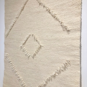 May include: A white woven wall tapestry with a diamond pattern. The diamond is outlined with a fringe detail.