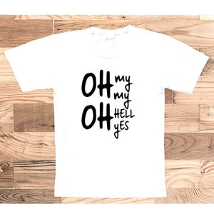 May include: White t-shirt with black text that reads "Oh my Oh my Hell Yes"