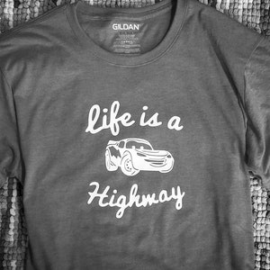 K&ouml;nnte beinhalten: Graues T-Shirt mit einer wei&szlig;en Grafik eines Cartoon-Autos und dem Text "life is a highway".