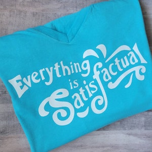 May include: A turquoise blue t-shirt with a white graphic that says "Everything is factual".