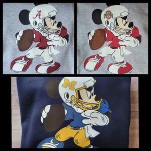 May include: Three different football jerseys featuring Mickey Mouse in a football uniform. The first jersey is gray with red and white accents and the text "A". The second jersey is gray with red and white accents and the text "Ohio State". The third jersey is navy blue with yellow and white accents and the text "M".