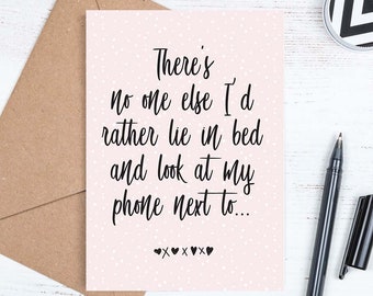 May include: A pink card with white polka dots and black text that reads "There's no one else I'd rather lie in bed and look at my phone next to..." with four black hearts at the bottom.
