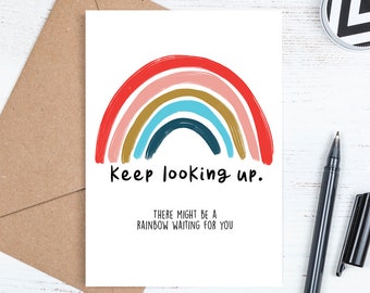 May include: A white card with a colorful rainbow painted on it. The text "Keep looking up. There might be a rainbow waiting for you" is printed below the rainbow.
