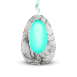 May include: White marble-look diffuser with a teal light emanating from the center. The diffuser is shaped like an egg.