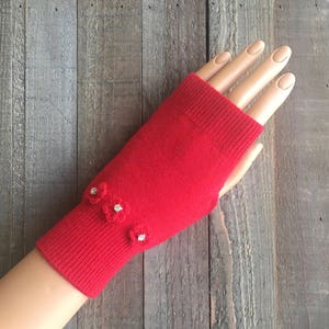 May include: Red fingerless gloves with small white flower embellishments.