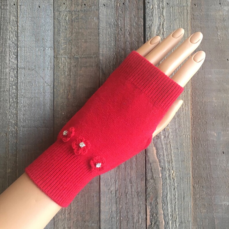 May include: Red fingerless gloves with small white flower embellishments.
