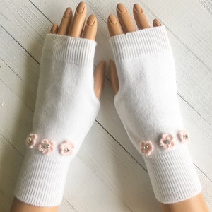 May include: White fingerless gloves with pink crocheted flowers and rhinestones.