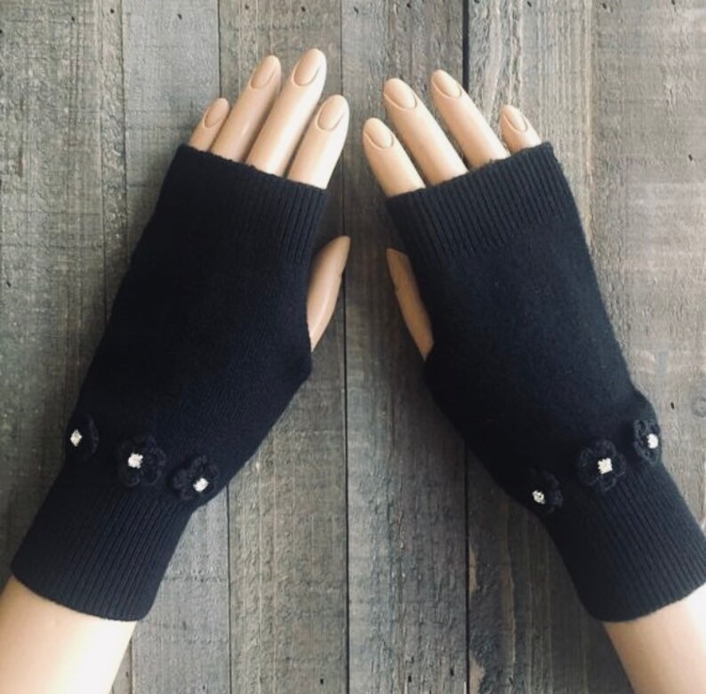 May include: Black fingerless gloves with white flower embellishments on the cuffs.