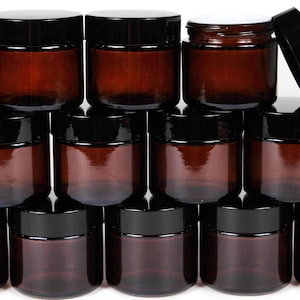 May include: A stack of 12 amber glass jars with black lids. The jars are arranged in a pyramid shape.