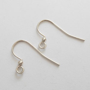 May include: Two silver-colored earring hooks. Each hook has a curved wire design with a small ball and a loop at the bottom. The hooks are designed for jewelry making and are displayed against a white background.